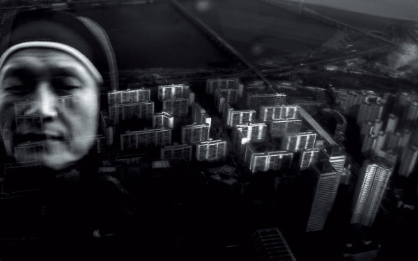 The black and white collage shows a nun in front of a bird's eye view on skyscrapers. 