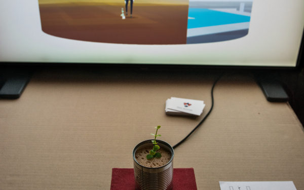 A plant grows out of a can that is connected to a screen.