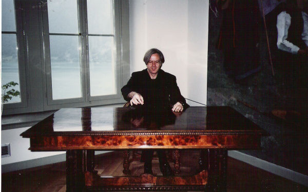 Fotografie von Gerhard Johann Lischka, hinter einem großen, schweren Schreibtisch sitzend