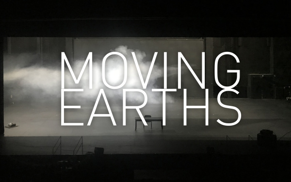 An abandoned stage with a table and a chair, from the left fog is streaming through the picture and it is written large in the foreground: "Moving Earths".