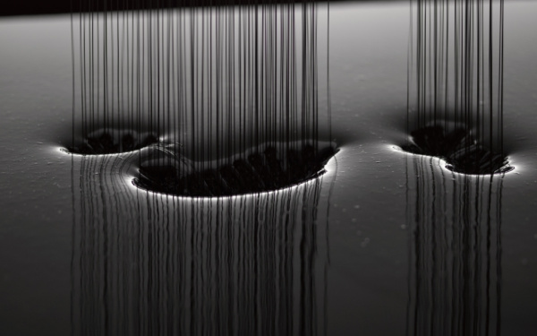 Black silicon oil drops into a bassin.