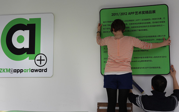 Zwei Menschen hängen eine grünes schild mit asiatischer Schrift auf