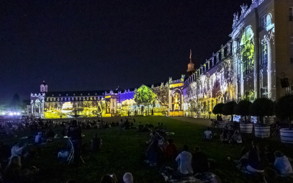 Various living environments are projected onto the façade of the three-winged Karlsruhe Castle.