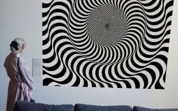Eine Frau steht hinter einem Sofa, vor einem Bild. Das Bild zeigt eine optische Täuschung aus schwarz, weißen Linien, die dem Auge eine Bewegung vorspielen.