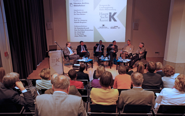 Besetzter ZKM_Vortragssaal mit Blick auf Teilnehmer der Podiumsdiskussion