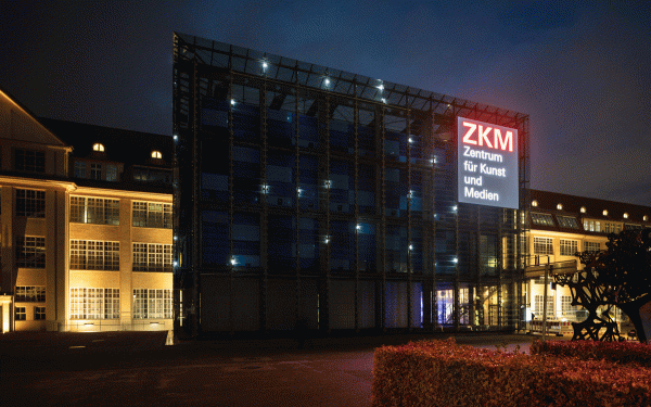 Der gläserne Kubus des ZKM funkelt im Dunkeln mit hellen Lichtpunkten. Eine Installation von Walter Giers.