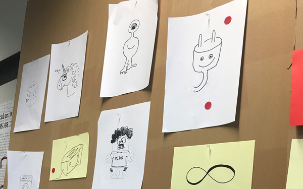 Drawings with possible chatbot characters on a pinboard.