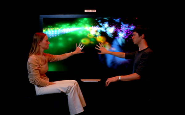 Two people touching an illuminated screen