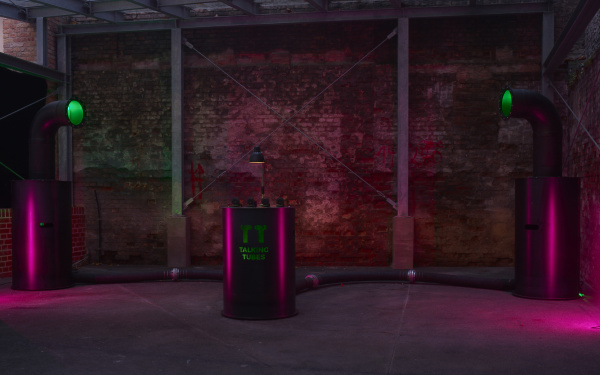 A red-lit room with the Talking Tubes installation: a control panel between two large tubes