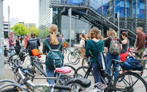 Eine Gruppe von Menschen hat sich mit ihren Fahrrädern vor dem ZKM Kubus versammelt