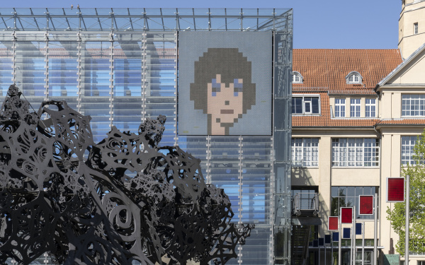 Crypto art: an illustrated face in pixel style on the LED wall of the ZKM Cube