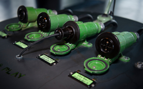 Four tube sockets lie side by side on a metal desk. One of them is wired. Labels are attached in front of them with something written on them.