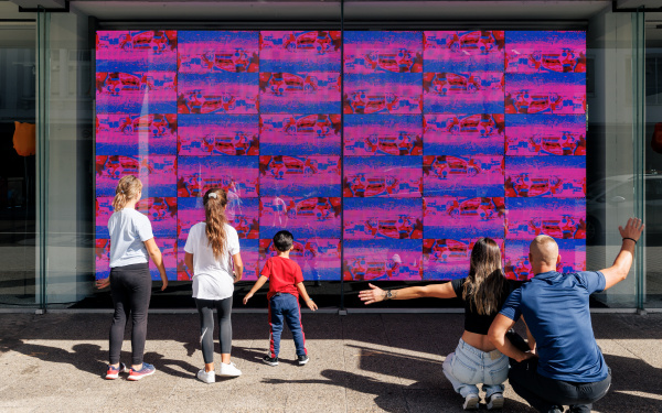 Auf dem Bild sieht man die Videoinstallation »footprint« von Jonas Denzel. Auf einem großen Screen sind lauter kleiner Bilder die von den Beinen von Passanten aufgenommen wurden. Eine fünfköpfige Familie steht davor und interagiert mit dem Kunstwerk.