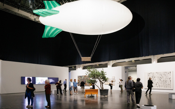 Zu sehen ist die Ausstellung »Soun-Gui Kim: Lazy Clouds« am ZKM. Oben im Raum schwebt ein Zeppelin.