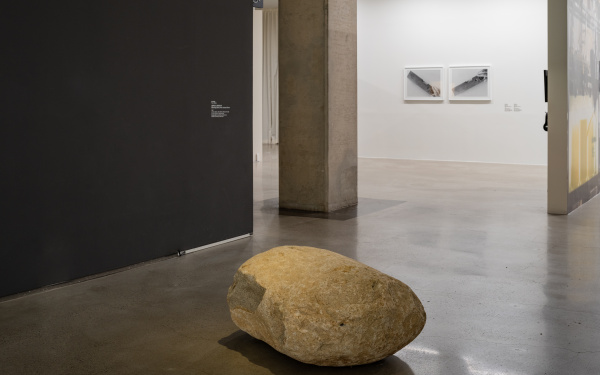 Zu sehen ist ein gelblicher Stein in einem Ausstellungsraum.