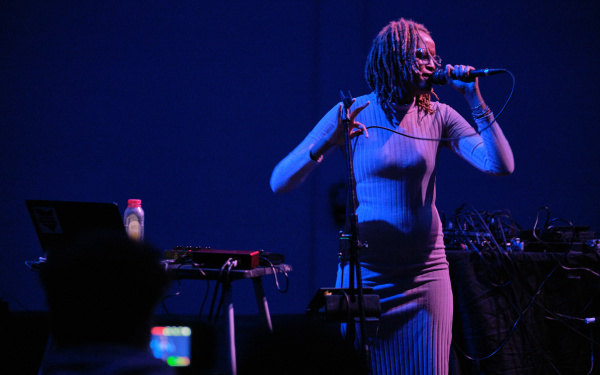 Nyokabi Kariuki stands in front of her set during a performance with microphone in hand