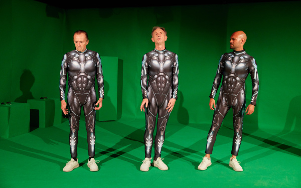 Three men in futuristic armor stand in a green-screen studio