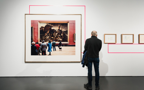 A person stands in front of a painting.