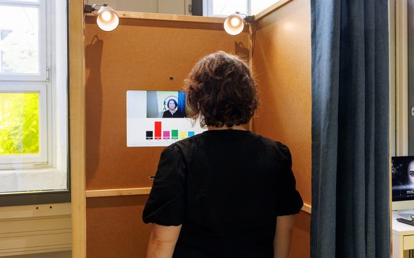 Eine Frau steht in der Wahlkabine "Smile to Vote – Political Physiognomy Analytics". Das Szenario simuliert t den Prozess der digitalen Stimmabgabe bei einer Bundestagswahl