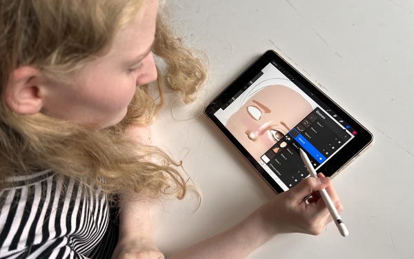 Eine Person zeichnet ein Gesicht auf einem Tablet.