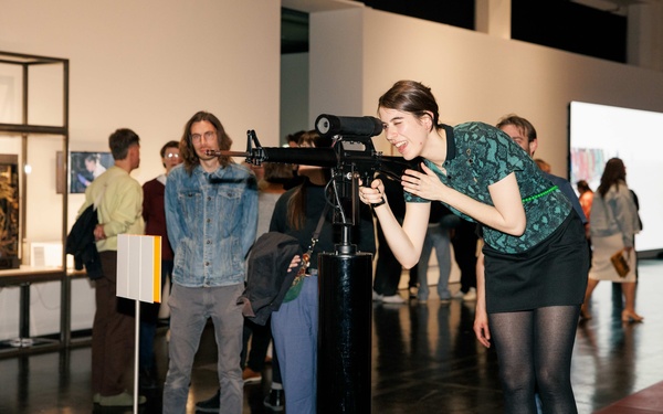 Person blickt durch die Zielvorrichtung einer interaktiven Installation in Form eines M16-Gewehrs von Lynn Hershman Leeson.