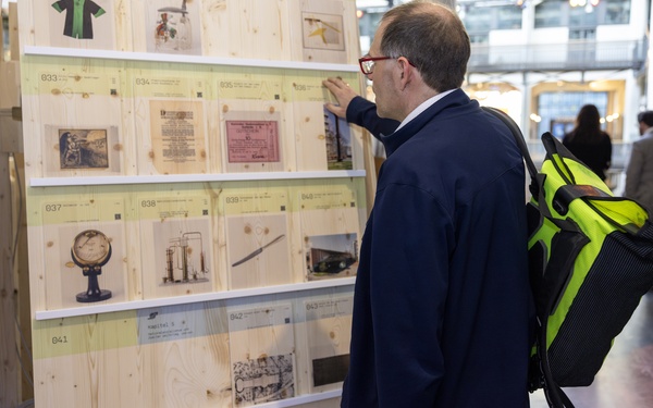 The picture shows a person standing in front of a stand with object cards.