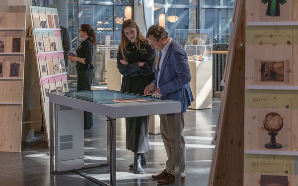 Two people can be seen looking at an object card on a table.