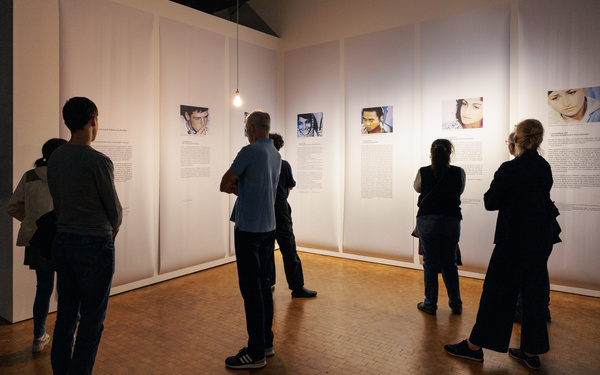 The picture shows people reading texts in an exhibition.