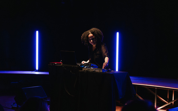 Zu sehen ist eine Person umgeben von blauem Licht, die Live-Elektronik aufführt.