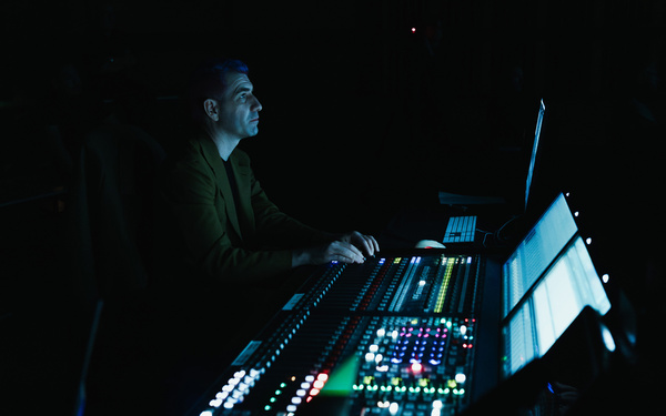 Zu sehen ist eine Person, die vor einem Mischpult sitzt. 