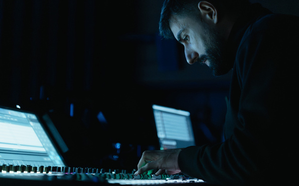 Zu sehen ist eine Person, die vor einem Mischpult sitzt. 