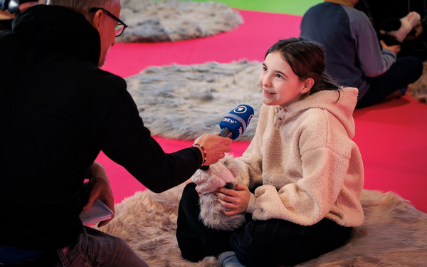 Child speaking into microphone in front of colorful background