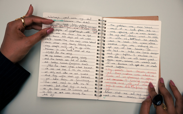 Zwei Hände blättern in einem Notizbuch.