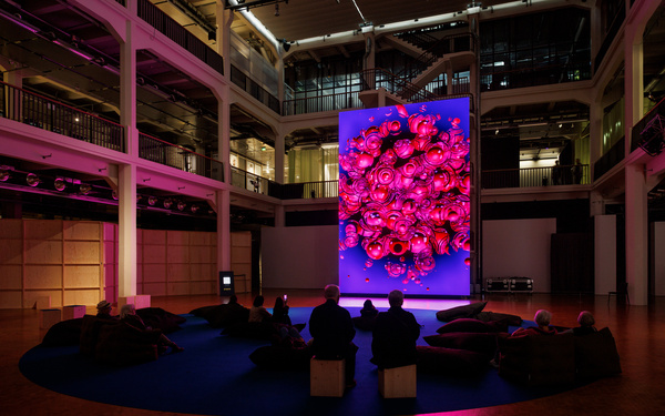 The picture shows a huge screen that several people are looking at. 
