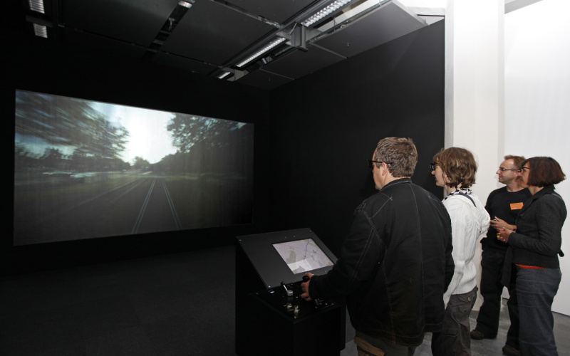 People stand in front of a screen, you should see on the tram rails