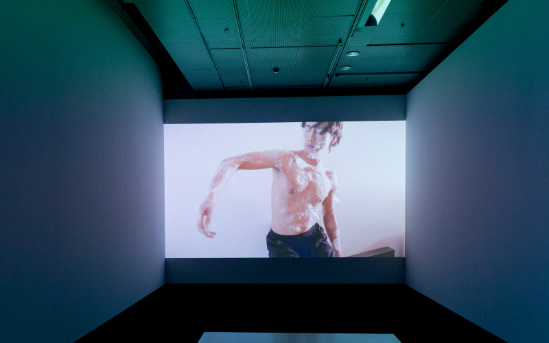 Einer Tänzer mit nacktem Oberkörper ist auf einem großen Screen zu sehen