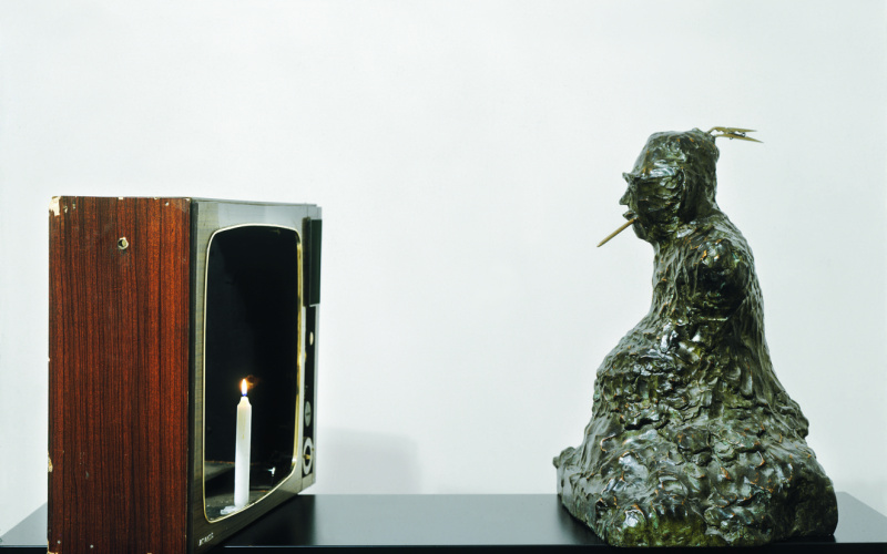 On the left side you can see the shell of an old tube television made of wood where a candle stands instead of the screen. Opposite is a Buddha figure with a toothpick in his mouth.