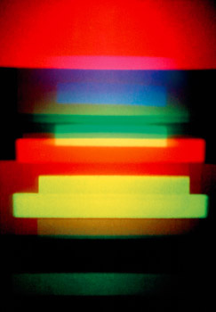 A holographic image by Dieter Jung. Red, blue, green and yellow horizontal stripes on a dark background.