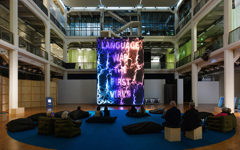 The image shows a huge screen that several people are looking at.